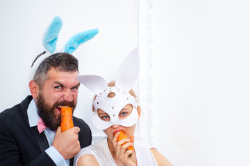 bearded man and sexy girl. copy space. Rabbits family with bunny ears. Holiday celebration, preparation. Easter bunny. happy easter. spring holiday. Egg hunt. easter bunny couple eat orange carrot