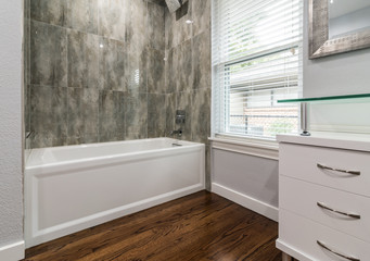 white Bathtub with Wood flooring and tile walls