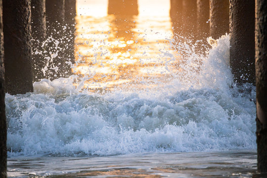 Waves crashing under the pier at sunrise
