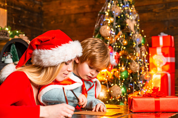 Mum and kid writing a letter to Santa with wish list of Christmas presents.Christmas interior. Merry christmas and happy new year. Bright New Years interior concept.