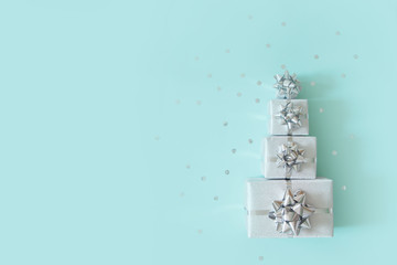 Christmas banner. Xmas silver and glitter gifts box, blue background. Christmas gift boxes laid out in the shape of a Christmas tree, overhead view