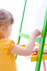 Happy baby girl beautiful painting on the easel on a white background