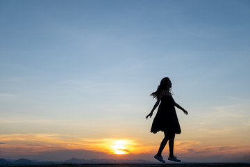Silhouette of free woman enjoying freedom feeling happy at sunset,dancing