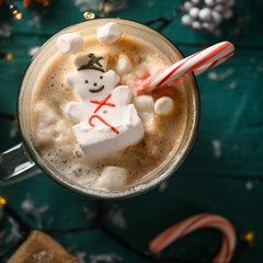 Christmas composition, mug with hot chocolate with melted snowman marshmallows and caramel. Square...
