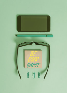 Word writing text Be Our Guest. Business photo showcasing You are welcome to stay with us Invitation Hospitality Dark eyeglasses colored sticky note smartphone pen clips pastel background