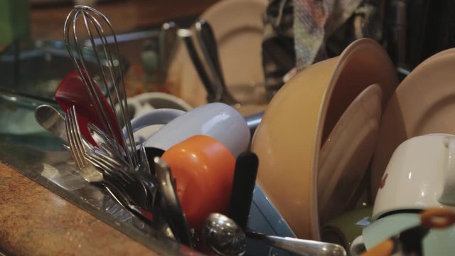 Slow tilting shot of unwashed dishes in sink at kitchen. 