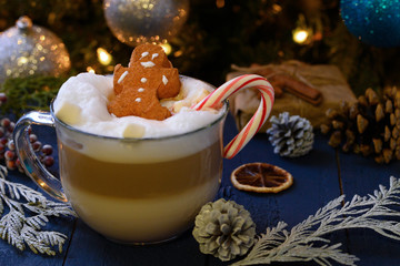 Christmas and New Year. Marshmallow snowman in hot latte in a mug. On the background of Christmas trees and toys.