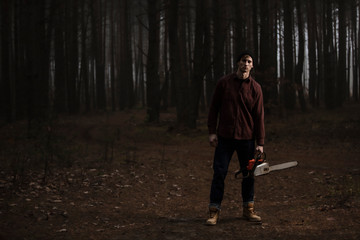 Lumberman working with chainsaw in the forest. Strong lumberjack with the chainsow in the...