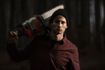 Lumberman working with chainsaw in the forest. Strong lumberjack with the chainsow in the...