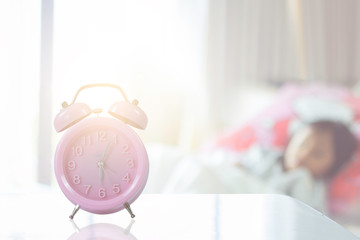 clock and child sleeping on bed