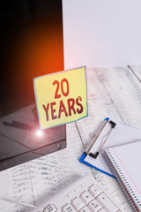 Text sign showing 20 Years. Business photo showcasing Remembering or honoring special day for being 20 years in existence Note paper taped to black computer screen near keyboard and stationary