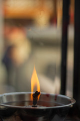 Single fire light lit and float on the oil lamp.Chinese shrine Fire Oil lantern in Thailand.Ancient sacred Buddishm temple way of life front portrait sway fire,old film look vintage background style.