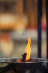 Single fire light lit and float on the oil lamp.Chinese shrine Fire Oil lantern in Thailand.Ancient sacred Buddishm temple way of life front portrait sway fire,old film look vintage background style.