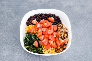 buddha bowl with fresh produce such as tomatoes corn bean kale and pulled jackfruit
