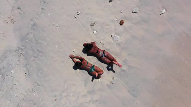 Samar Island, Philippines - Two Attractive Woman Sunbathing and Relaxing On the Shore Under the Bright Sunny Day  - Aerial Shot 