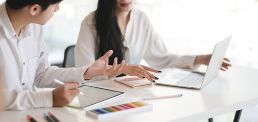 Cropped shot of young professional designer team working on her project while using digital tablet and laptop computer in modern office