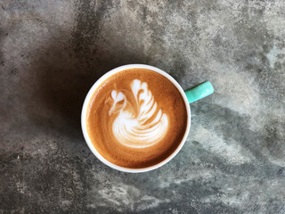 Swan shape latte art coffee in white and green cup on cement floor with natural light ; love coffee, Top view and copy space.