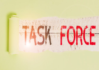 Conceptual hand writing showing Task Force. Concept meaning a group of showing who are brought together to do a particular job Cardboard which is torn placed above a wooden classic table