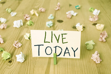 Conceptual hand writing showing Live Today. Concept meaning spend your life doing what you want Live in the present moment Colored crumpled papers wooden floor background clothespin
