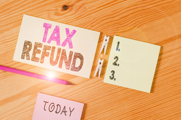 Conceptual hand writing showing Tax Refund. Concept meaning refund on tax when the tax liability is less than the tax paid Colored crumpled papers wooden floor background clothespin