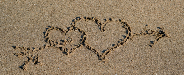 Hand drawn two Hearts on a golden sand. Drawing in sand for Happy Valentines Day, wedding, Love inspirational quote. Romantic love concept. Expression of emotions. Couple of hearts with arrow. 