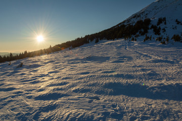 Traveling tourists on the snowy winter mountain ranges of the Ukrainian Carpathians with beautiful views of the evening peaks.