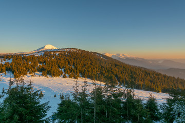 Traveling tourists on the snowy winter mountain ranges of the Ukrainian Carpathians with beautiful views of the evening peaks.