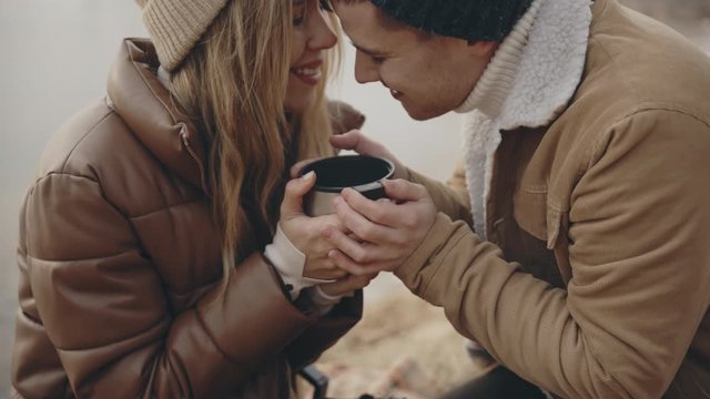Hiker couple in love drinking tea from a thermos at chilly autumn day. Hiking, travel, family, love, sport, lifestyle, trekking concept. Filmed on cinema camera. 12 bit color space.