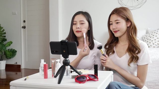 Portrait of young asian woman review giveaway gift product fan following channel, recording video make up lipstic cosmetic at home. Beauty blogger present beauty cosmetics