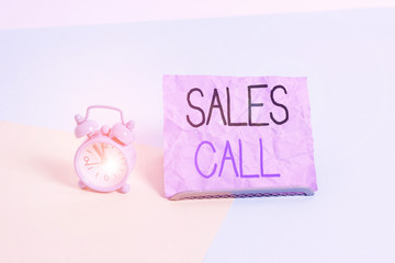 Handwriting text writing Sales Call. Conceptual photo a phone call made by a sales representative of a company Mini size alarm clock beside a Paper sheet placed tilted on pastel backdrop