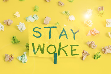 Handwriting text writing Stay Woke. Conceptual photo being aware of your surroundings and things going on Keep informed Colored crumpled papers empty reminder white floor background clothespin