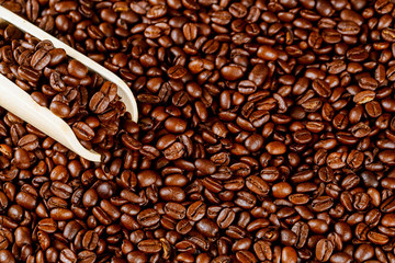 Aromatic black coffee beans with wooden spoon. Close up.