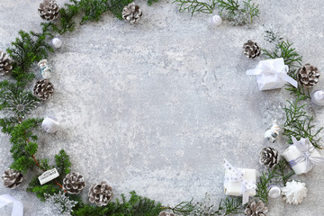 Christmas frame of evergreen,pine cones,giftboxes,ornaments, on gray background. Flat lay, top view, copy space.