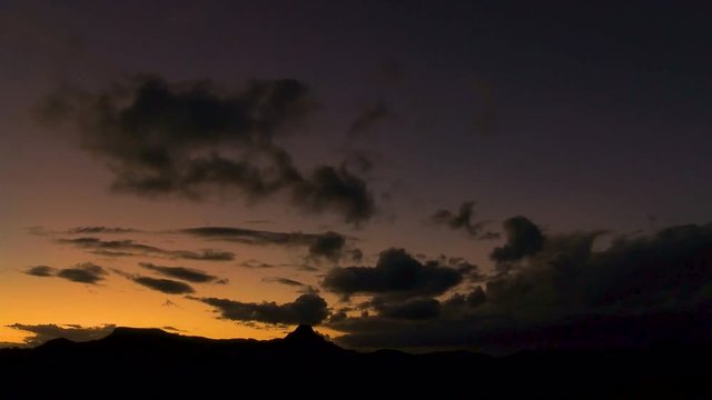 Peaceful and calm sunset timelapse of purple clouds over golden sky