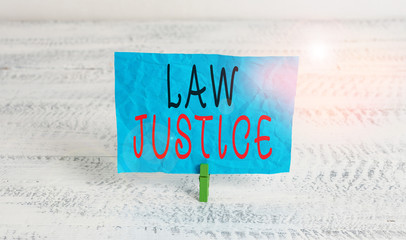 Word writing text Law Justice. Business photo showcasing a scheme or system of law in which every demonstrating receives Green clothespin white wood background colored paper reminder office supply