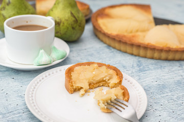 Delicious home bake poached pear tart pie, as known as Tarte Bourdaloue, a cup of coffee latte. French popular recipe that gets the name from a street in Paris. Food on table concept.