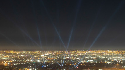 Spotlights in the Night Sky with Beams of Light in a Small City