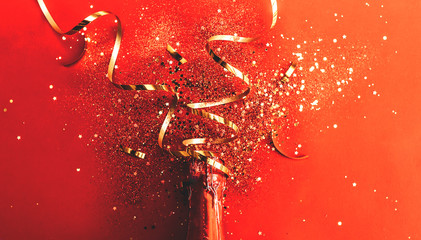 Bottle of red champagne with gold glitter, sparkles, confetti on red background, top view. New year background. flat lay. © Anastassiya 