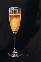 One glass of glittering champagne on black background. Sparkles in beverage on black background. Happy New Year.