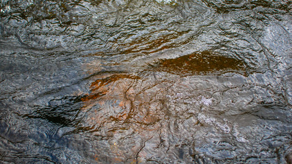 the surface of the water on the mountain river and the rocks on the bottom