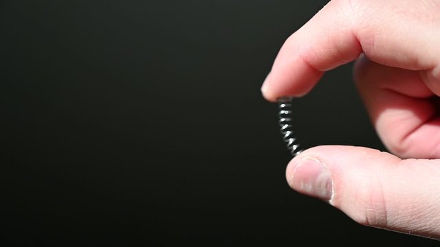 finger and thumb compressing a metal spring