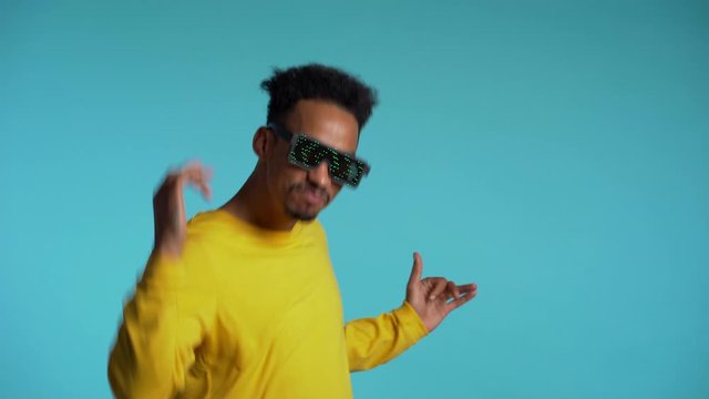 African american man in glowing glasses dancing with hands isolated on blue background. Party, music, lifestyle, radio and disco concept.