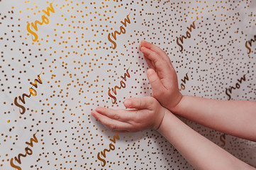hands on white wrapping paper with gold foil patterns and the inscription snow