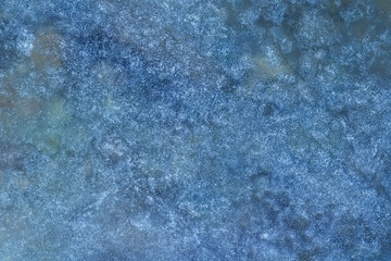 blue texture of an ice surface with pure azure water ,cold snow cryslallized wall background ,winter frozen lake side close up , abstract macro wallpaper