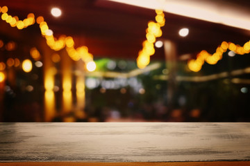 background Image of wooden table in front of abstract blurred restaurant lights