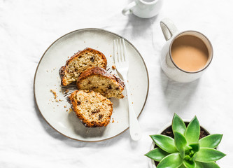 White and milk chocolate banana oatmeal cake, coffee, succulent flower on a light table background, top view. Delicious breakfast, snack, dessert