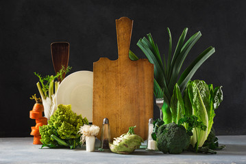 Still life kitchen board with fresh vegetables on dark background. Healthy food concept