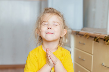 Portrait of a little praying girl indoors
