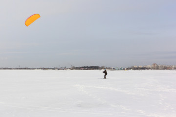 Kiteboarder with orange kite on the snow, Ob reservoir, Novosibirsk, Russia