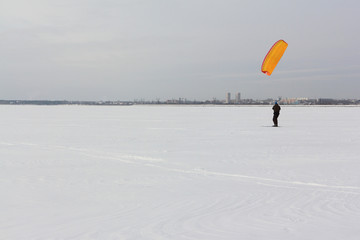 Kiteboarder with orange kite on the snow, Ob reservoir, Novosibirsk, Russia